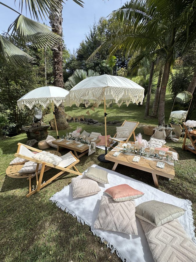 Picnic boho con sombrillas de macramé en un jardín tropical